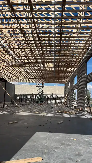 Framing crew working from a scissor lift under the truss deck of a commercial building