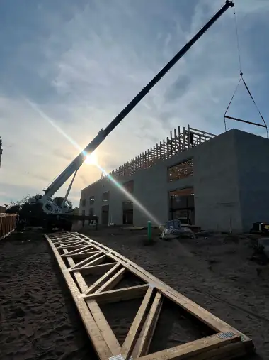 Crane setting engineered trusses at golden hour on a Central Florida commercial building