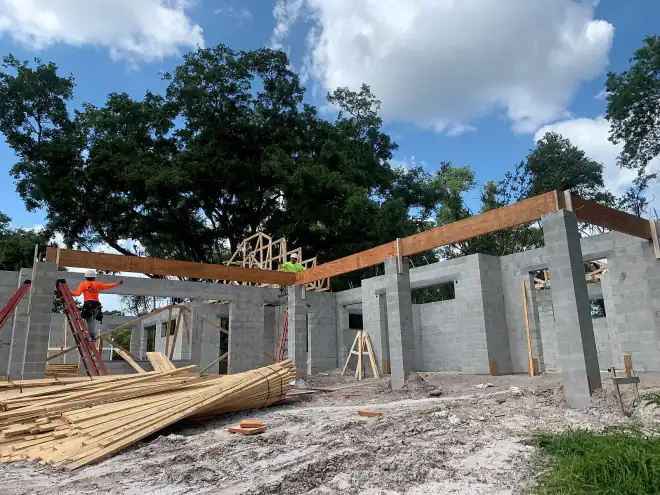 Concrete block walls and staged lumber as a beam is set on a Central Florida custom home site