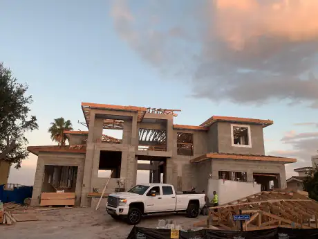 Two-story modern custom home framed and sheathed with lumber staged in front, Central Florida