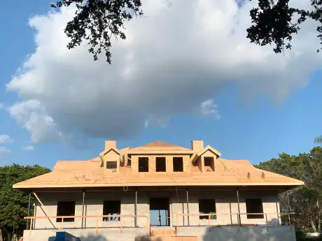 Large estate home fully framed with dormers and a wraparound porch, seen from the drive