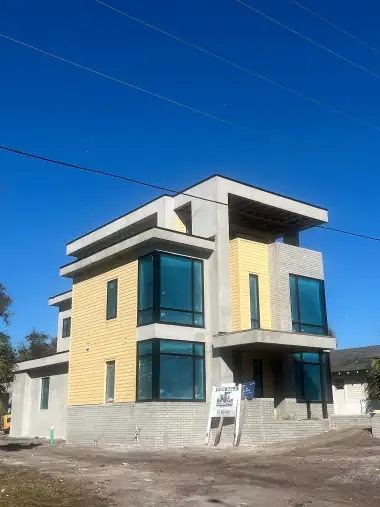 Finished three-story modern home with stucco, floor-to-ceiling glass and wood-look siding