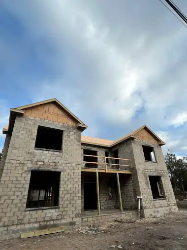 Two-story build with concrete block below and wood framing above under a cloudy sky