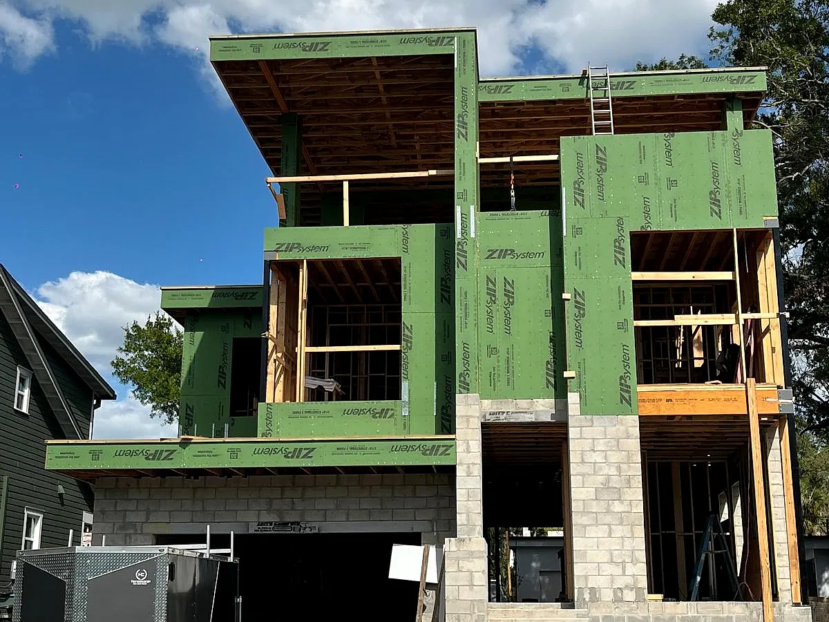 Modern custom home framed with green sheathing panels and deep cantilevered overhangs