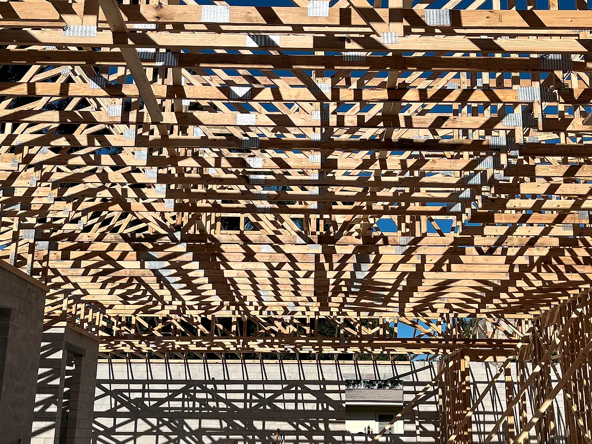 Row of engineered wood roof trusses set on block walls against the sky